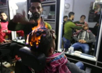 A Palestinian barber uses fire to straighten the hair of a customer in Rafah in the southern Gaza Strip. REUTERS/Ibraheem Abu Mustafa