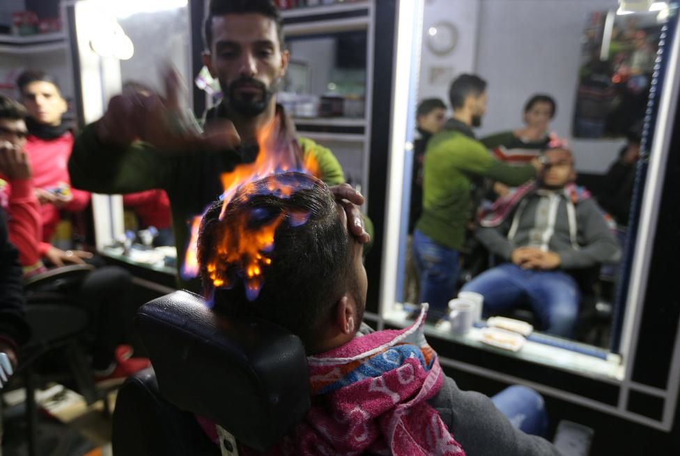 A Palestinian barber uses fire to straighten the hair of a customer in Rafah in the southern Gaza Strip. REUTERS/Ibraheem Abu Mustafa