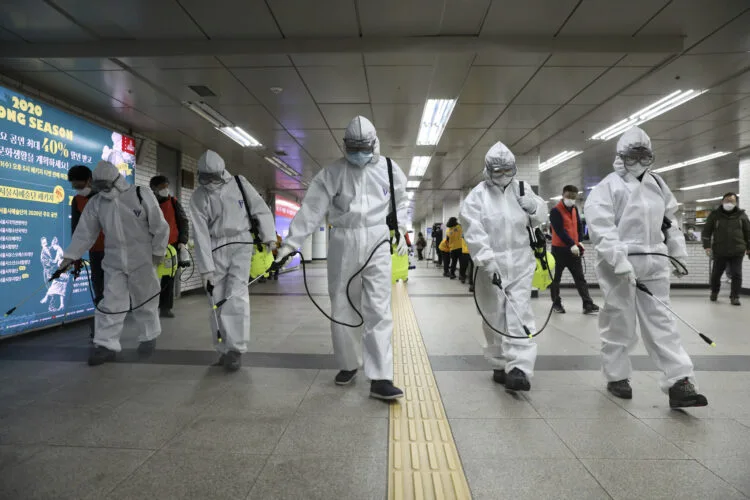Workers wearing protective gears disinfect as a precaution against the new coronavirus at the subway station in Seoul, South Korea, Wednesday, March 11, 2020. (Kim Sun-woong/Newsis via AP)