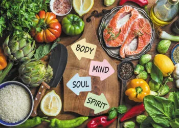 Dinner cooking ingredints. Raw uncooked salmon fish with vegetables, rice, herbs and spices over rustic wooden background, top view, copy space. Chopping board in center