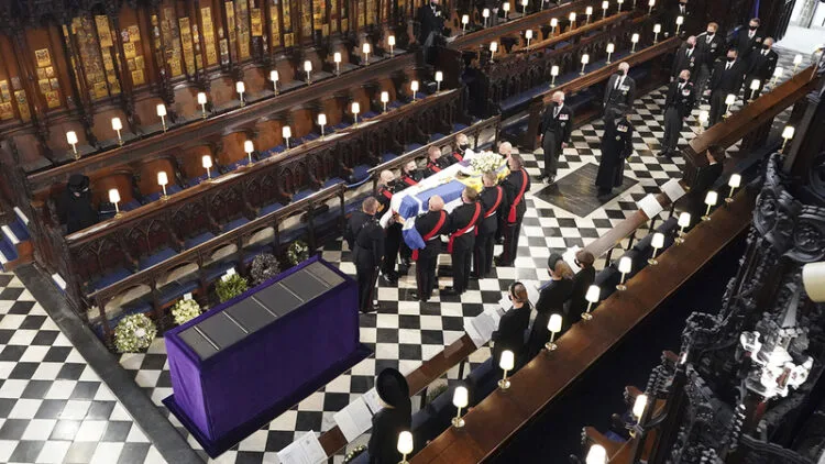 Britain's Queen Elizabeth watches as pallbearers carry the coffin of the Duke of Edinburgh during his funeral at St George's Chapel in Windsor Castle, Windsor, England, Saturday April 17, 2021. Prince Philip died April 9 at the age of 99 after 73 years of marriage to Britain's Queen Elizabeth II. (Dominic Lipinski/Pool via AP)